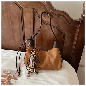 Gros plan du sac hobo en daim marron avec pampilles colorées et forme de demi-lune