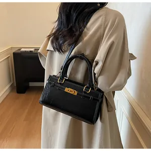 Sac à main chic en cuir noir avec fermoir doré et bandoulière porté à l'épaule
