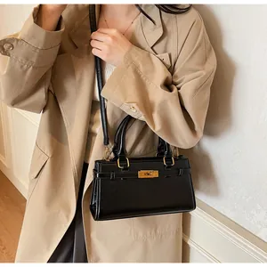 Détail d'un sac à main noir chic avec ferrures dorées porté sur un trench-coat beige