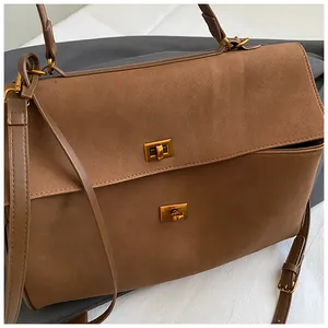 Detail of brown suede tote bag with double gold twist locks and adjustable shoulder strap