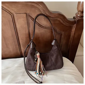 Détail du sac hobo rétro en daim marron café avec des pampilles colorées élégantes