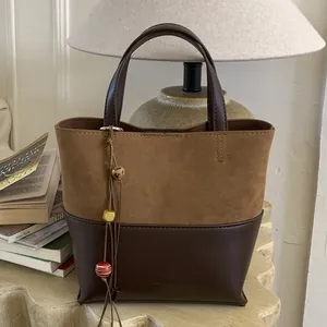 Retro patchwork tote bag with suede texture and beaded tassel charm on a display stand