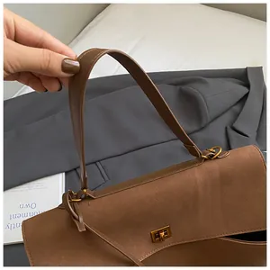 Detail shot of brown suede shoulder bag featuring a golden square twist lock buckle
