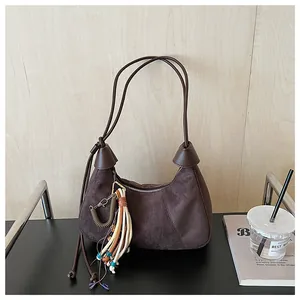 Gros plan d'un sac bandoulière en daim rétro avec pompon ethnique et forme demi-lune