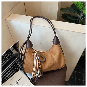 Détail du sac hobo en daim marron avec pompon bohème coloré et décoration de perles