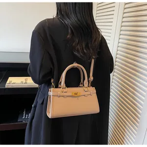 Détail d'un sac à bandoulière en cuir beige avec boucle dorée sur un blazer noir