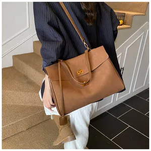 Detail of a large brown matte shoulder bag featuring gold buckle and dual strap options