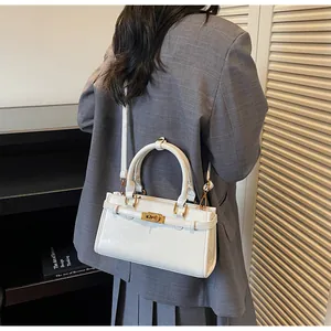 Détail du sac à bandoulière blanc avec boucle dorée et bandoulière réglable sur le côté