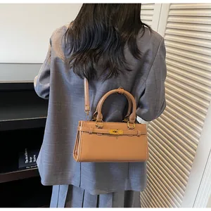 Détail du sac à main en cuir marron clair porté par un mannequin en veste grise