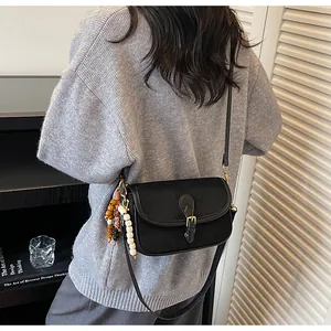 Detailed view of a retro black matte crossbody bag with unique wooden bead charm detail