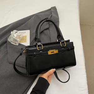 Détail d'un sac à main en cuir noir avec fermoir rotatif doré et bandoulière texturée