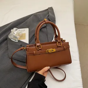 Détail du sac à main en cuir marron foncé avec fermoir doré et doubles poignées