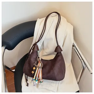 Détail du sac croissant en daim marron avec pampille colorée et charms en perles