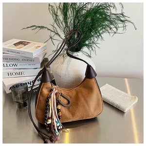 Détail du sac hobo en daim marron avec breloques à franges colorées et bandoulière