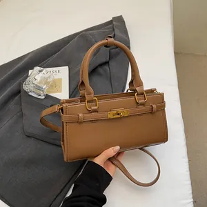 Détail d'un sac à main marron avec fermoir rotatif métallique et bandoulière réglable
