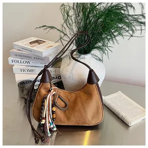 Détail d'un sac hobo en daim marron avec gland ethnique et garniture en cuir