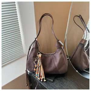 Détail d'un sac demi-lune en daim marron avec pendentif à franges de style rétro chic