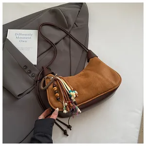 Gros plan du sac en daim marron avec pompon en perles ethniques et garniture en cuir