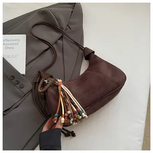 Détail d'un sac hobo en daim marron avec un gland coloré de style bohème et perles