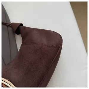 Détail d'un sac bandoulière en daim marron foncé avec coutures fines et sangle tissée