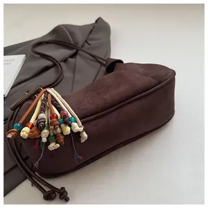 Détail du sac bandoulière en daim marron rétro avec des glands colorés en perles