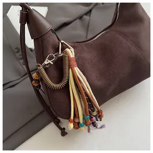 Gros plan du sac demi-lune en daim marron foncé avec breloque perlée et fine bandoulière