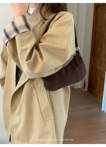 Dettaglio della borsa a tracolla in pelle scamosciata marrone scuro con un trench beige