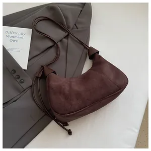 Détails d'un sac hobo en daim marron avec coutures apparentes et bandoulière en corde minimaliste