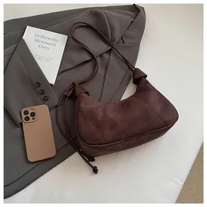 Vue détaillée du sac croissant en daim marron avec accessoires de mode et bandoulière