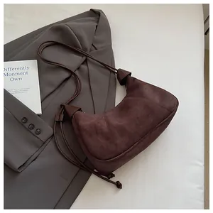 Détails d'un sac demi-lune en daim marron foncé avec bandoulière nouée et finition mate douce