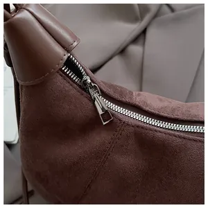Gros plan du zip et de la texture d'un sac bandoulière en daim marron foncé style