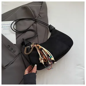 Détail d'un sac demi-lune en daim noir avec pampille ethnique et perles colorées
