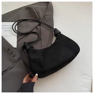 Détail du sac lune en daim noir minimaliste montrant la texture et la bandoulière