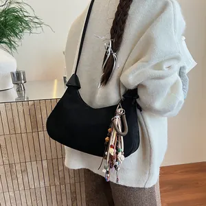 Sac bandoulière rétro en daim noir avec pendentif ethnique coloré sur un mannequin