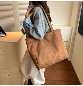 Detailed view of a large brown faux suede tote bag worn on shoulder in a minimalist room