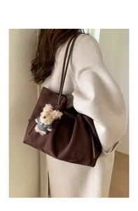 Detail of coffee brown suede tote bag featuring a cute plush bear pendant accessory
