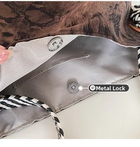Detail view of magnetic hardware clasp and herringbone fabric lining in a tote bag