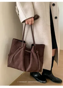 Detailed view of dark brown faux suede tote bag with side drawstring knot and retro texture