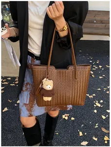 Detail of brown woven tote bag texture with cute teddy bear charm in autumn setting