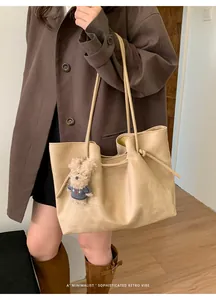 Detail of beige faux suede tote bag with cute bear charm and thin shoulder straps