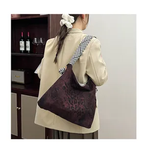 Detail of vintage leopard print tote bag with striped shoulder strap on model