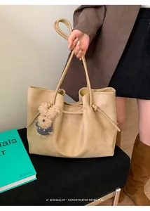 Detail of sand suede tote bag featuring side drawstring pleats and a cute puppy charm