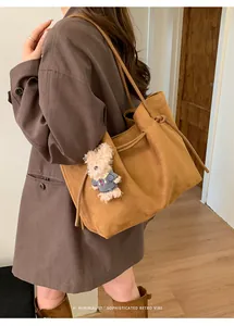 Brown suede tote bag with cute teddy bear charm shown on a stylish autumn trench coat