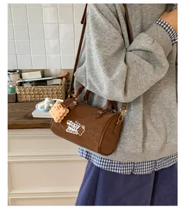 Detail of brown leopard print Boston bag with cartoon bear and plush cookie charm