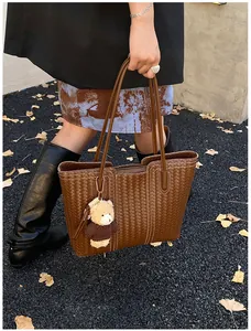 Detail of brown woven tote bag with Intrecciato texture and cute plush bear charm