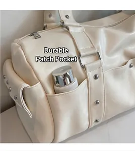 Detail of cream travel bag side pocket with silver rivets and utility storage space