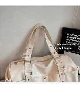 Detail of cream travel bag featuring reinforced handles and metallic rivet accents