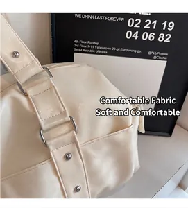 Close-up of cream white PU leather tote showing silver rivets and metal ring buckles