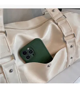 Detail view of durable side pocket on cream travel bag holding a smartphone
