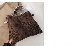 Detail of leopard print tote bag with striped handles and knot design on khaki blazer